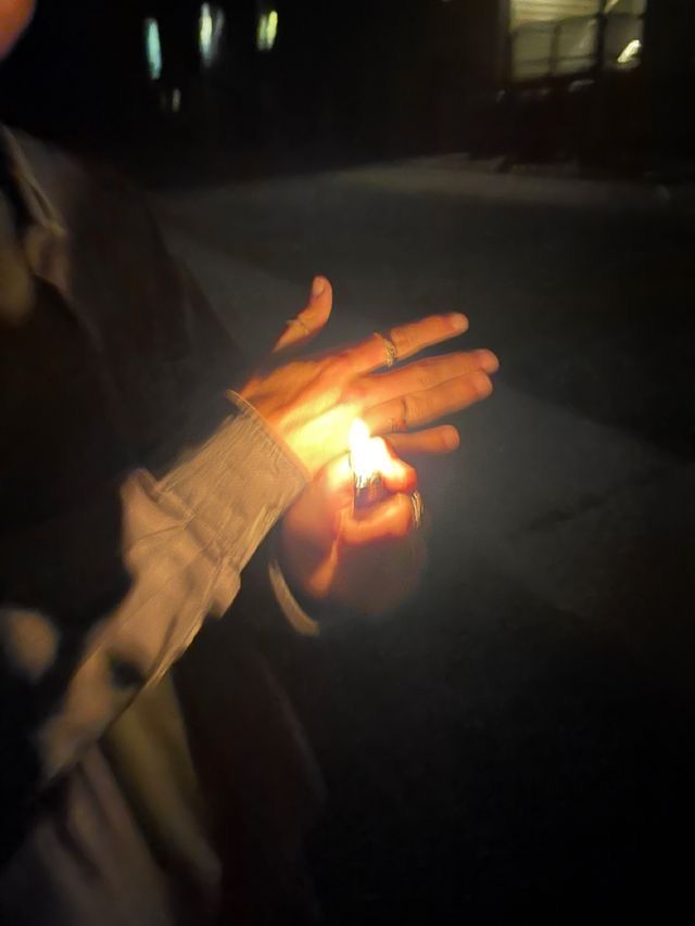 a person holding a lit candle in their hand on the street at night with no one around