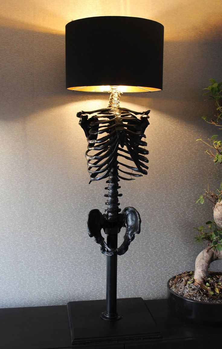 a lamp that is sitting on top of a black table next to a potted plant