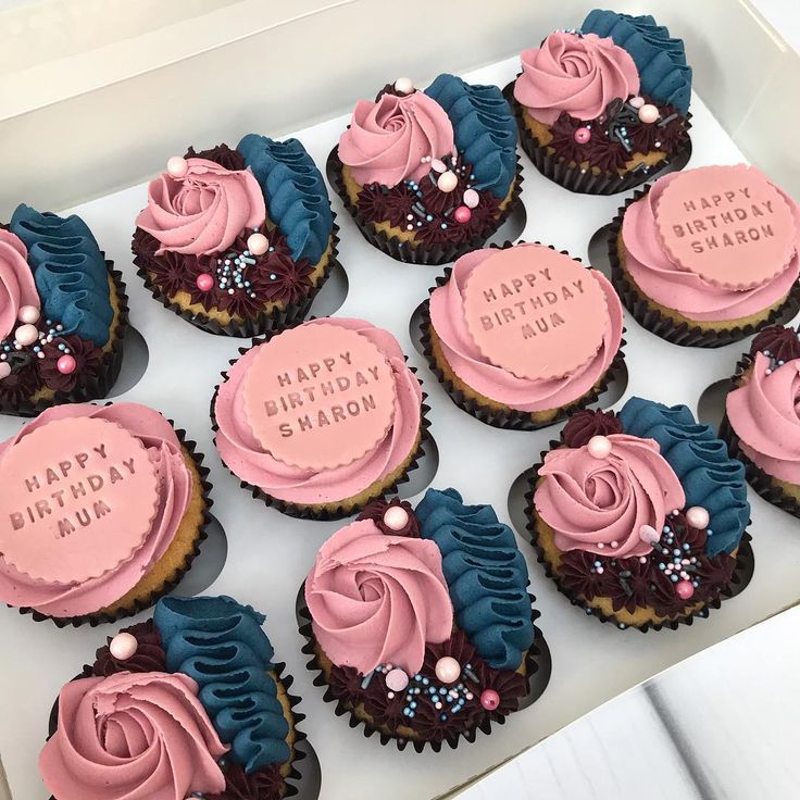 cupcakes with pink frosting and blue icing are arranged in a box