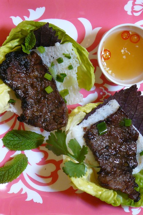 two lettuce wraps with meat and sauce on a pink floral plate next to a cup of tea