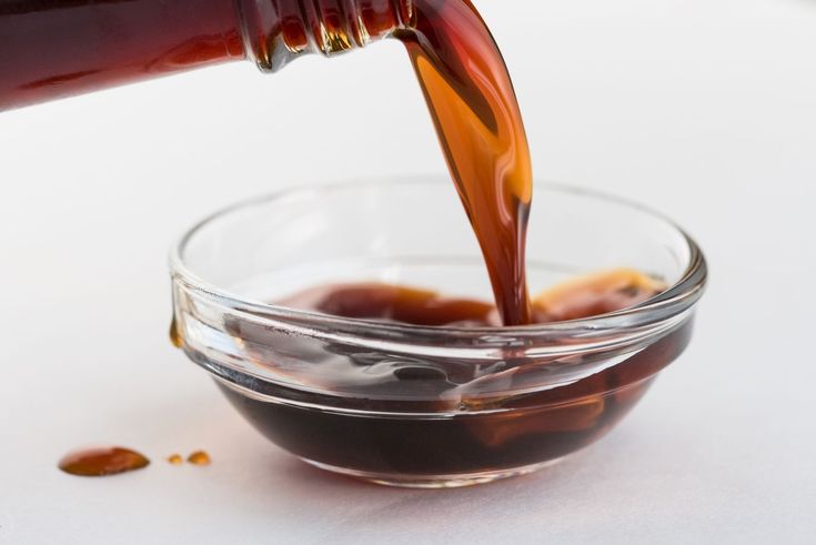 a person pouring sauce into a glass bowl