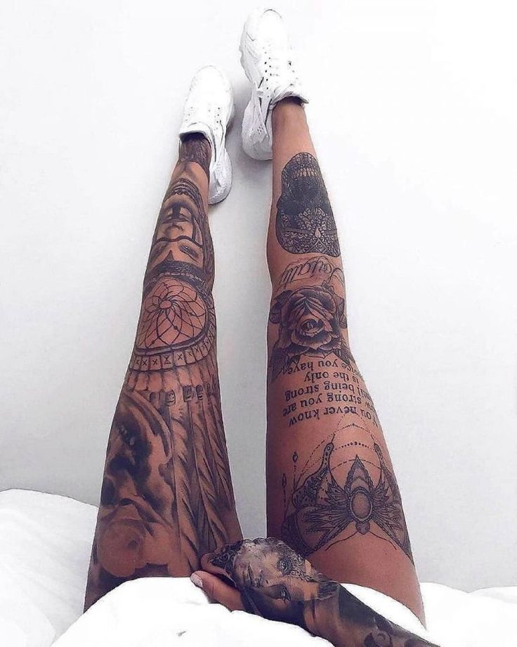 a person with tattoos on their legs and feet sitting on top of a white bed