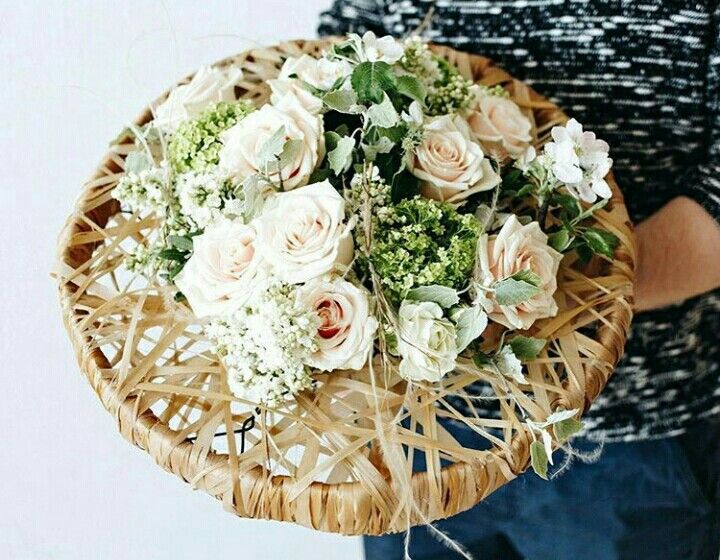 a person holding a wicker basket with flowers in it