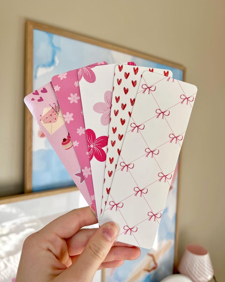 a person holding four different colored cards in their hand, with one folded up and the other closed