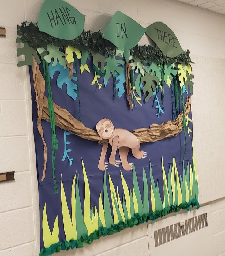 a bulletin board with paper cut out of animals and trees on the wall in front of it