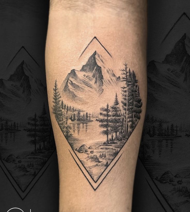 a tattoo on the leg of a person with mountains and trees in the background,