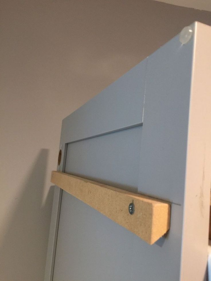 a close up of a refrigerator door with a wooden handle on the bottom and an unfinished shelf above it