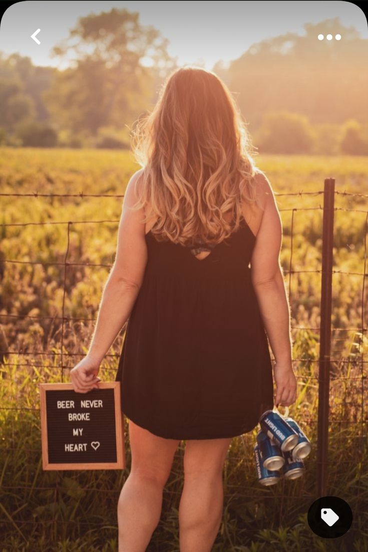 a woman standing in front of a fence holding a can and a sign that says beer never my heart