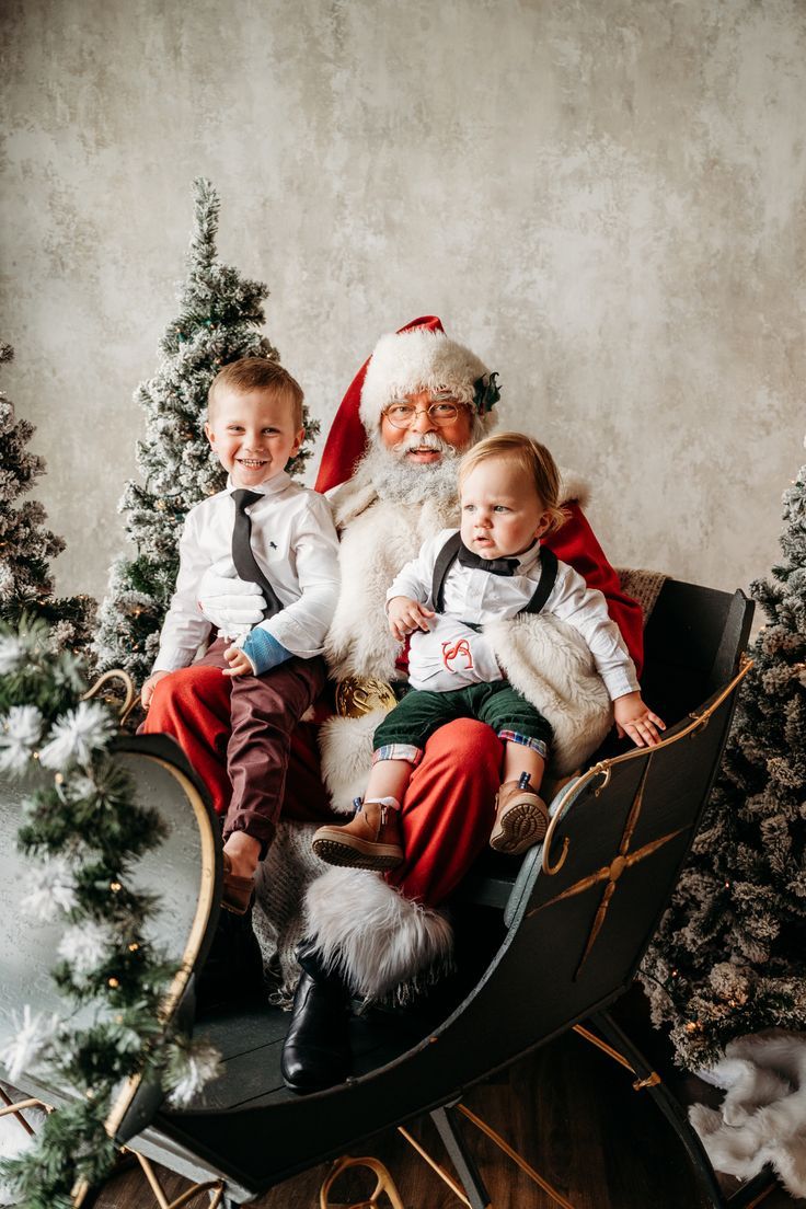 two children sitting in a sleigh with santa claus