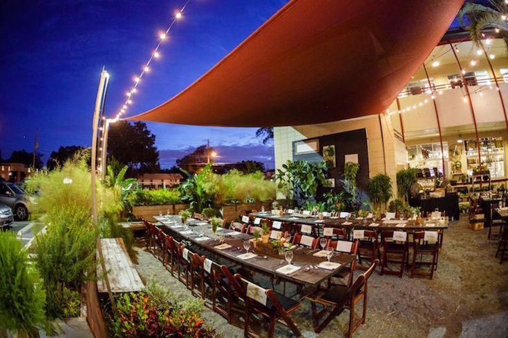 an outdoor dining area is lit up at night with string lights strung from the roof