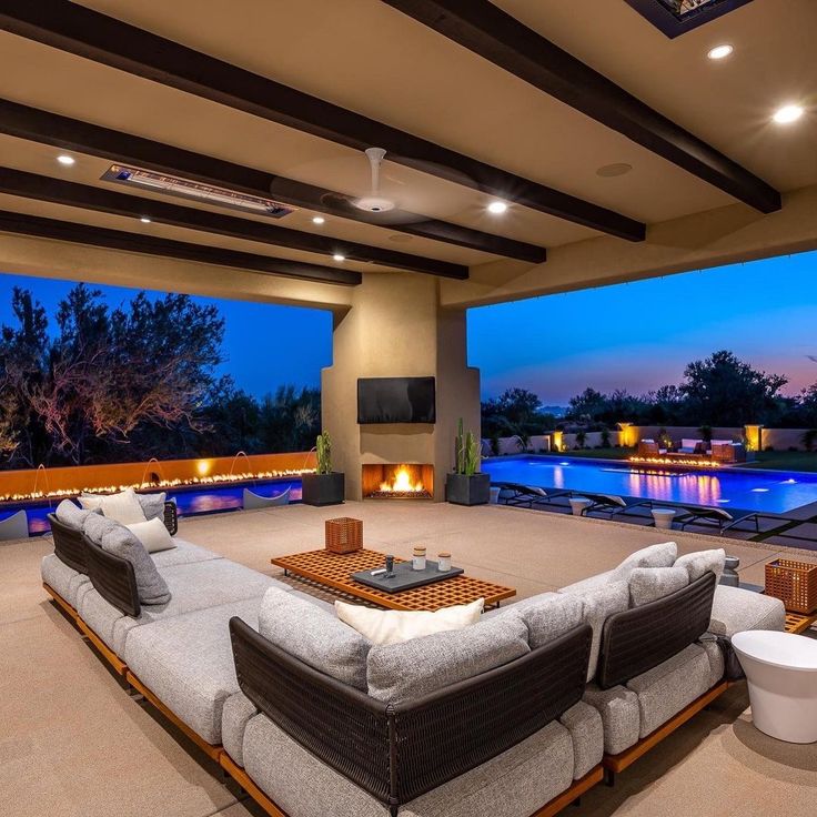 a living room with couches, tables and fireplaces next to a swimming pool