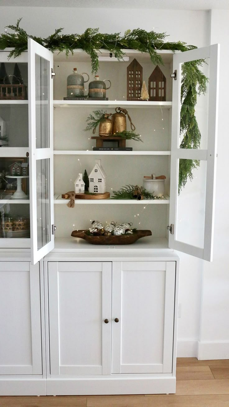 a white china cabinet with christmas decorations and greenery