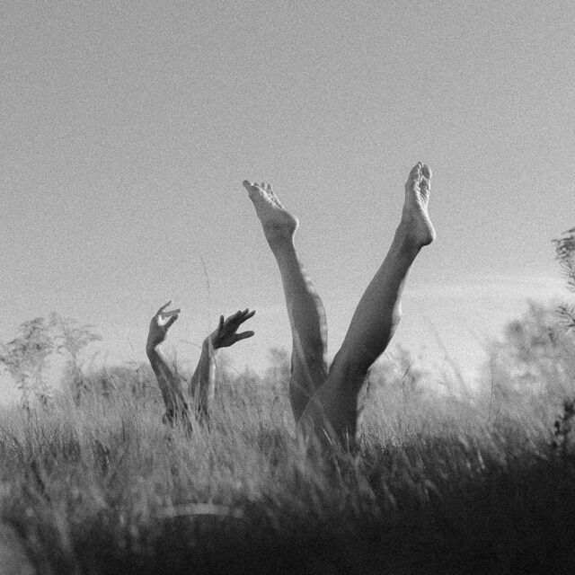 three people reaching up into the air to catch a frisbee in a field