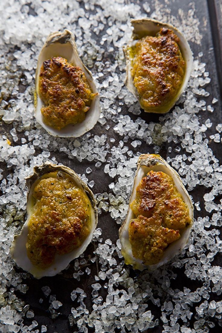 four raw oysters on a tray covered in sea salt and seasoning sprinkles