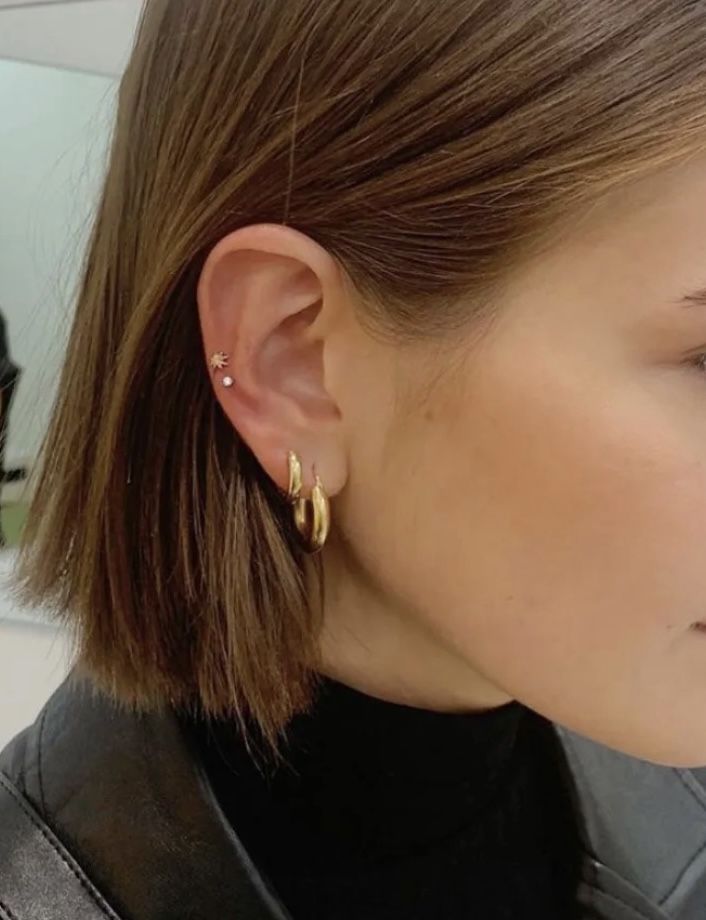 a close up of a person wearing some kind of gold earring on their left ear