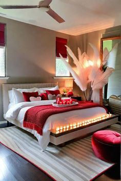 a bedroom decorated in red, white and grey with a bed that has candles on it