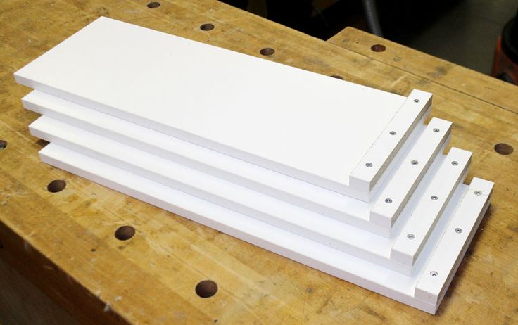 four pieces of white paper sitting on top of a wooden table with holes in it