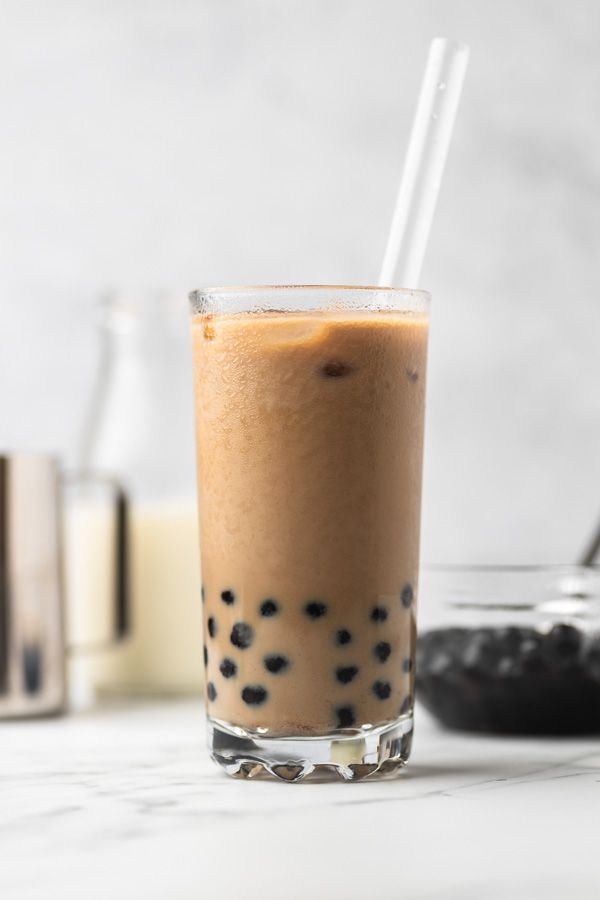 a drink in a glass sitting on top of a table next to some cookies and milk