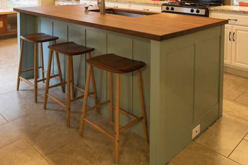 a kitchen island with three stools in front of it