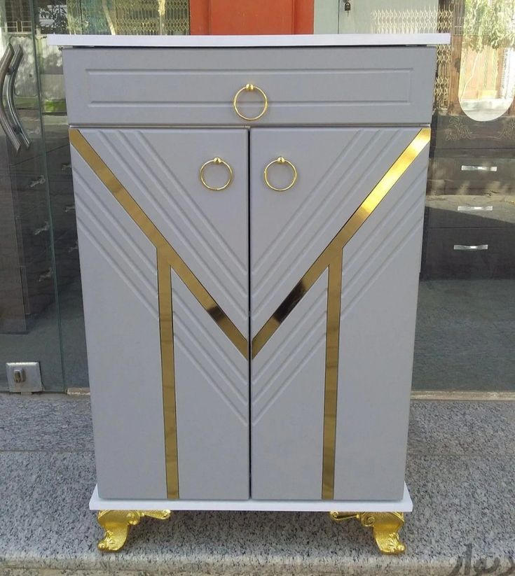 a white and gold cabinet sitting on top of a sidewalk