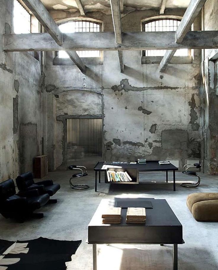 an industrial living room with concrete walls and exposed ceilings, black leather chairs and coffee table