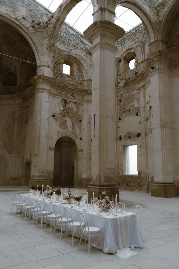 a long table is set up in the middle of an old building with arches and windows