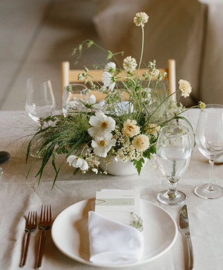 the table is set with white flowers and silverware