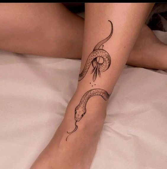 a woman's leg with a snake tattoo on her left arm and the other foot