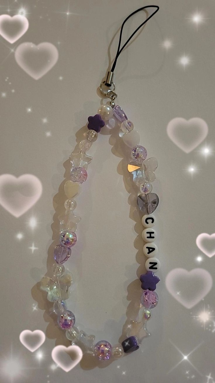 a necklace with beads and charms hanging from it's side on a white surface