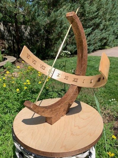 a wooden sculpture sitting on top of a metal barrel in the middle of a field