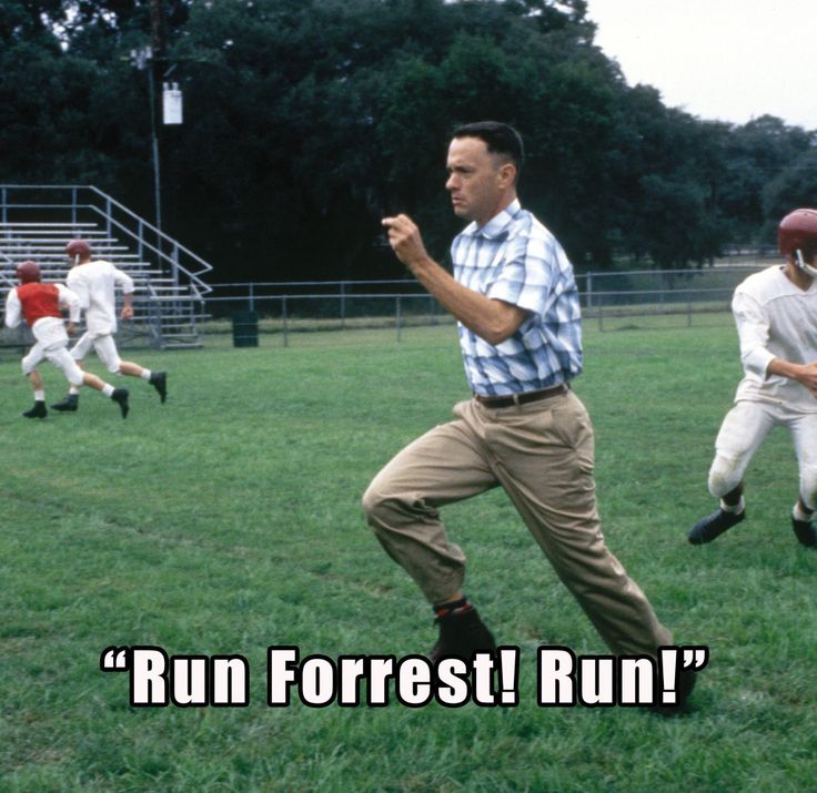 a man running across a lush green field next to other men in white and red uniforms