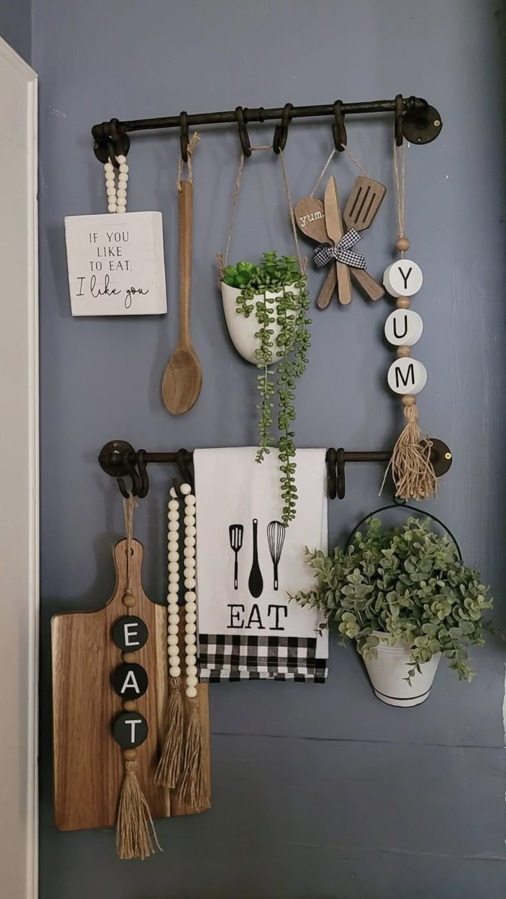 kitchen utensils are hanging on the wall next to a potted plant and wooden spoons