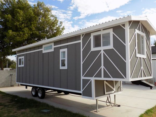 a gray and white tiny house sitting on the side of a road