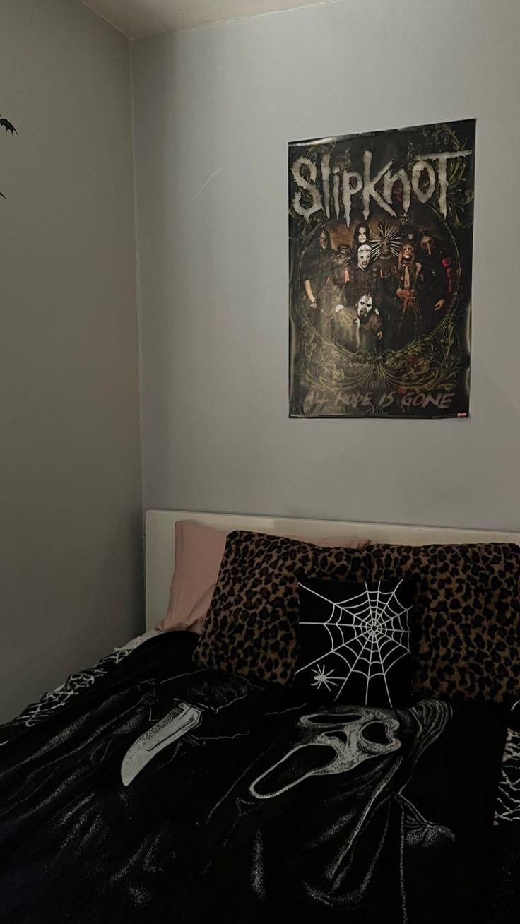 a bed with a black comforter and a poster on the wall above it that says slipknot