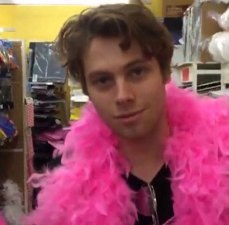 a young man wearing a pink feather boa