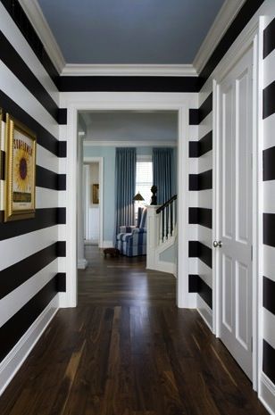 a hallway with black and white stripes painted on the walls, wood flooring and wooden floors