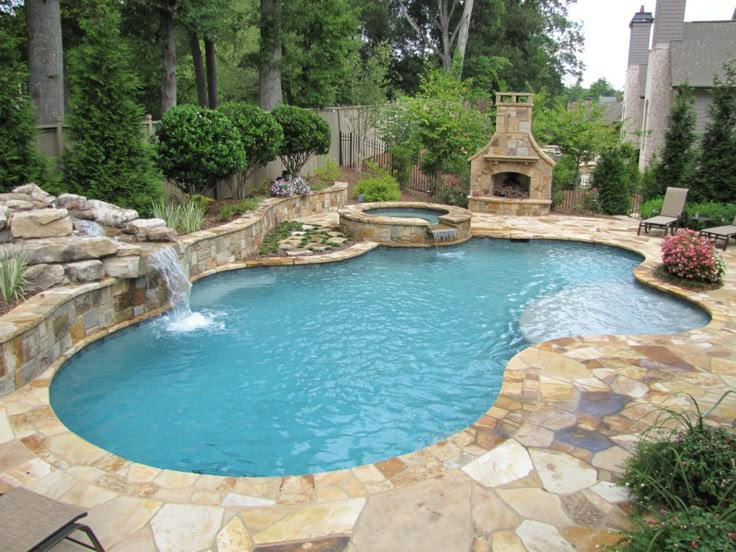 a pool with a waterfall in the middle and a fire place next to it, surrounded by trees