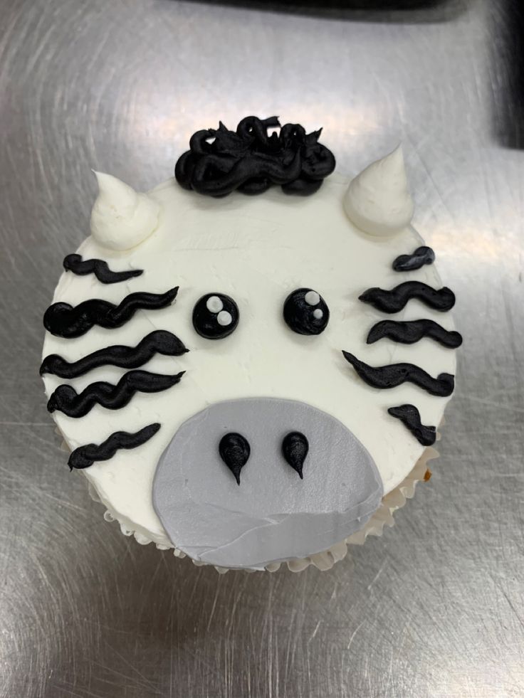 a cupcake shaped like a cow with black and white icing on it's face