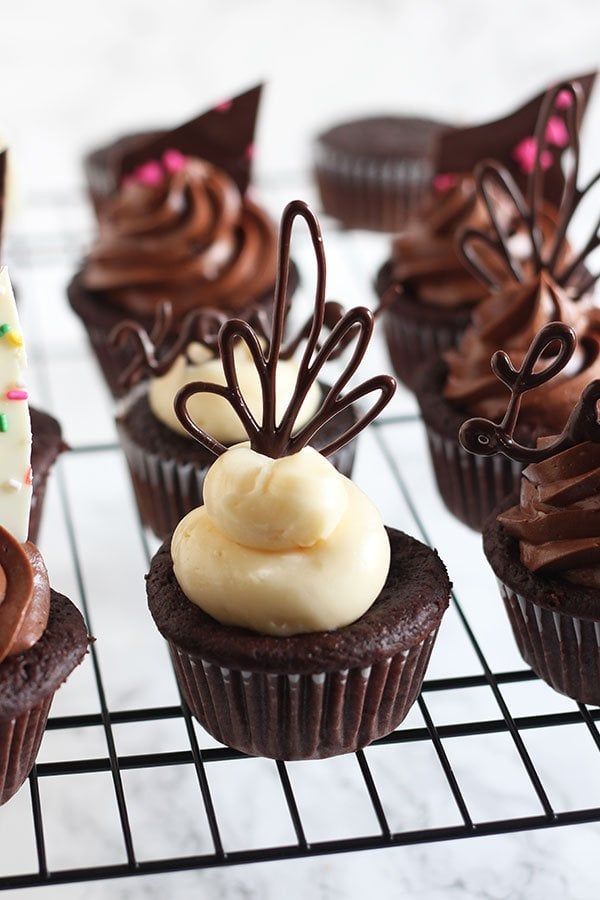 chocolate cupcakes with frosting and sprinkles on a cooling rack