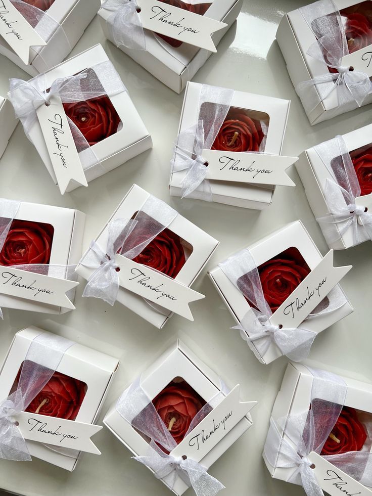 red roses in white boxes with ribbons tied around the edges and name tags on them