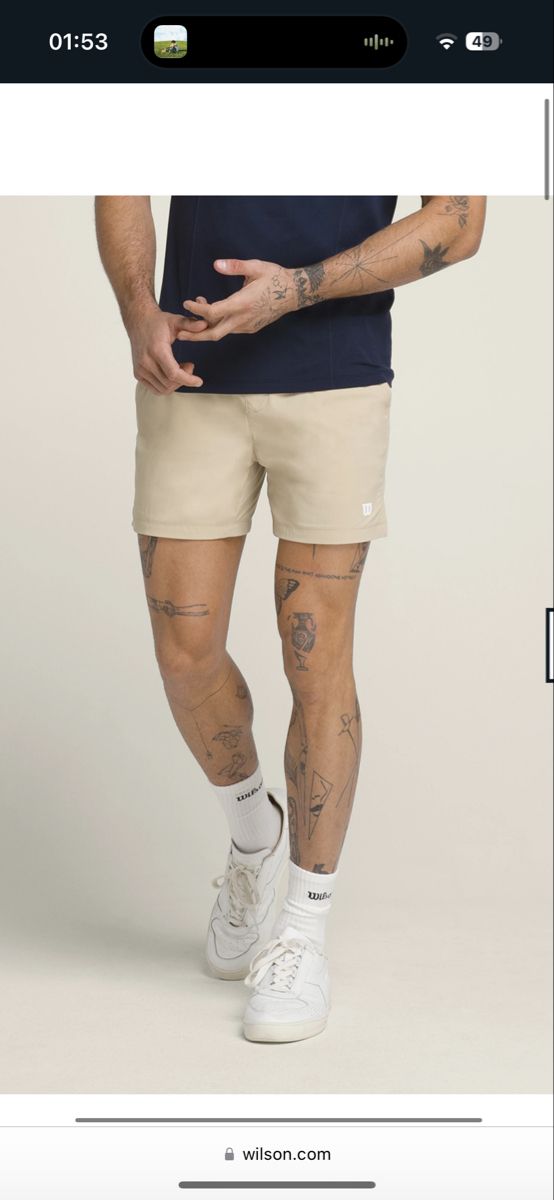 an image of a man with tattoos on his legs and leggings, standing in front of a white background