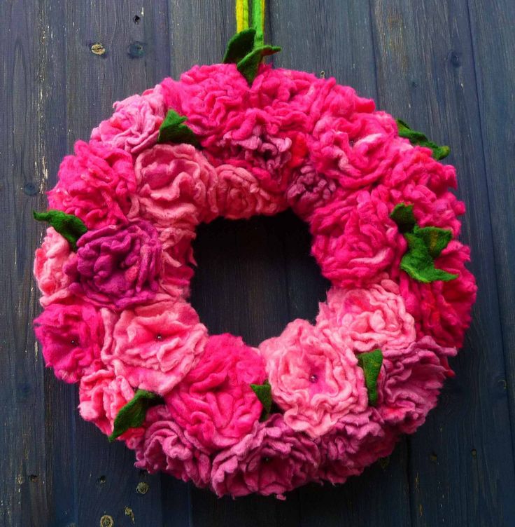 a pink wreath with green leaves and flowers