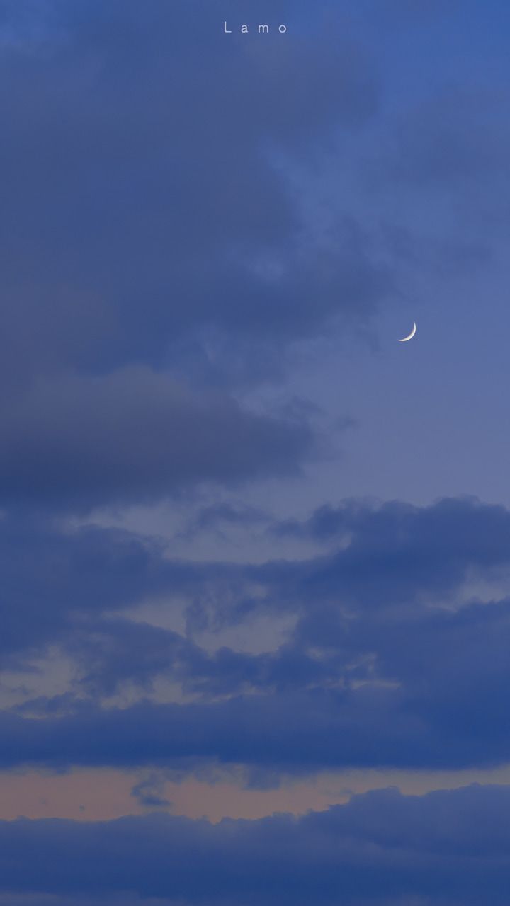 an airplane is flying in the sky at night with a half moon visible above it