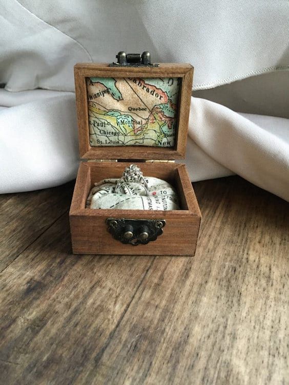 a small wooden box with a map in it on a table next to a pillow