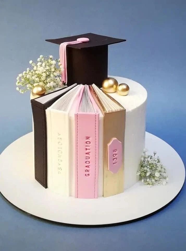 a graduation cake with books and flowers on top