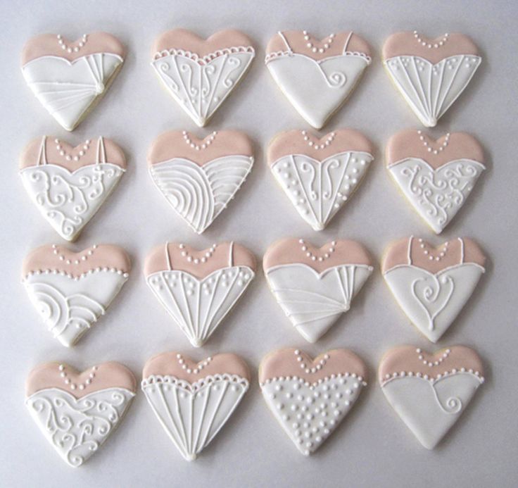 twelve heart shaped cookies decorated with white and pink icing