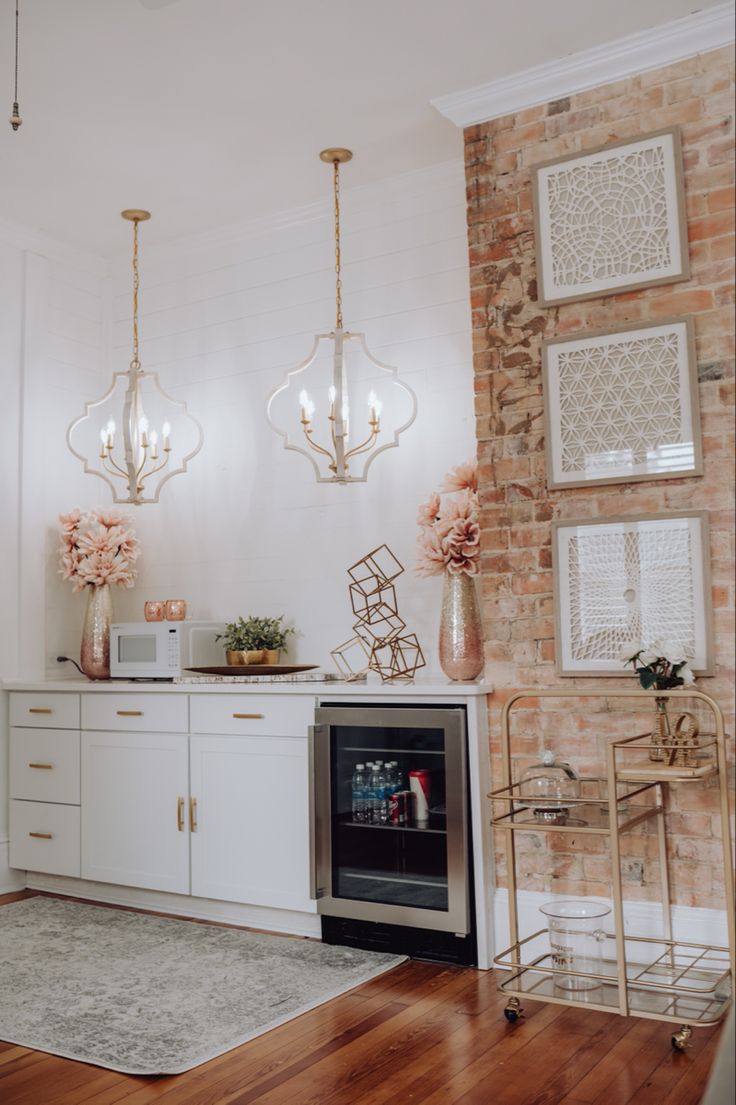 a kitchen with white cabinets and wooden floors, chandeliers above the stove top