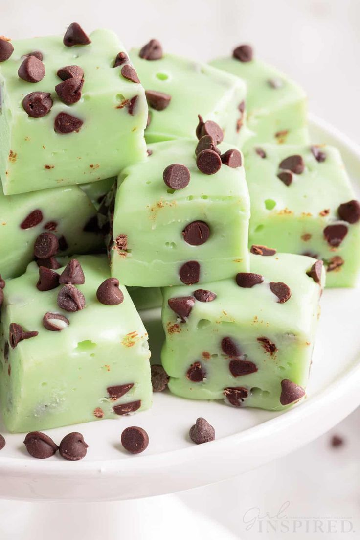 a white plate topped with green chocolate fudges covered in chocolate chips and mint