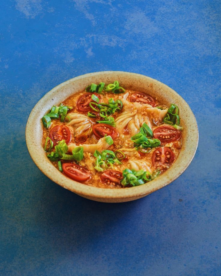 a bowl filled with food sitting on top of a blue table