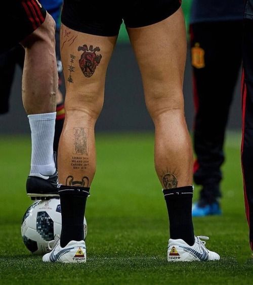 legs with tattoos and soccer balls on the field